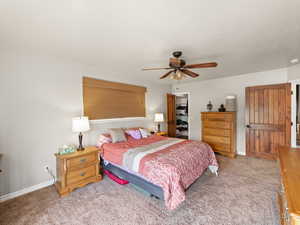 Bedroom with carpet flooring, a spacious closet, and a ceiling fan