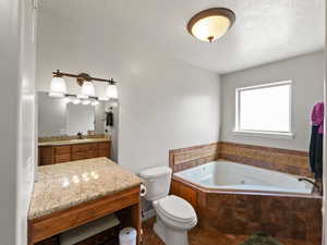 Bathroom featuring jetted tub, vanity, and tile flooring