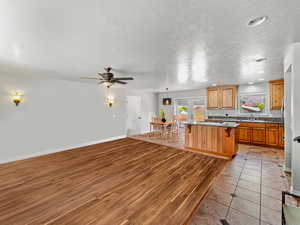 Kitchen featuring a textured ceiling, open floor plan, kitchen bar, nook, and hanging light fixtures