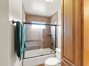 Full bath with bath / shower combo with glass door and a textured ceiling