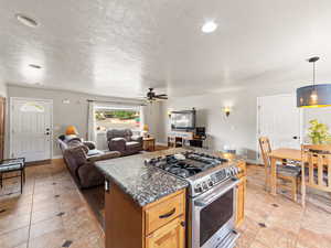 Kitchen with gas range, light tile patterned floors, open floor plan, a center island, and a textured ceiling