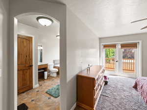 Bedroom featuring access to deck, a textured ceiling, ensuite bath, and light carpet