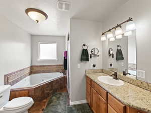 Full bath with a jetted tub, vanity, and tile floor