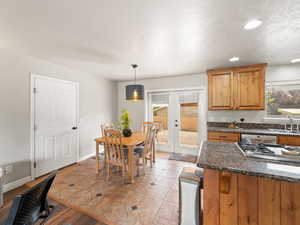 Kitchen with plenty of natural light, french doors, appliances with stainless steel finishes, a textured ceiling, and brown cabinets