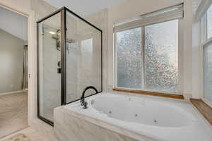 Owner's Suite bathroom featuring a marble finish shower and a whirlpool tub