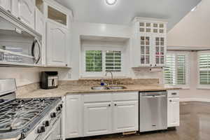 Kitchen with glass insert cabinets, stainless steel appliances, healthy amount of natural light, white cabinets, and a textured ceiling