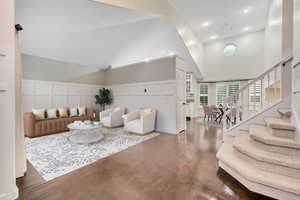 Entryway with recessed lighting, dark wood-style flooring, high vaulted ceiling, stairs, and a decorative wall. Virtually staged photo