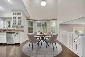Dining room with dark wood-style flooring, a towering ceiling, and a textured ceiling. Virtually staged photo