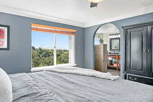 Bedroom with a ceiling fan, a textured ceiling, and arched walkways