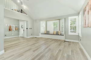 Unfurnished living room featuring wood tiled floors and high vaulted ceiling