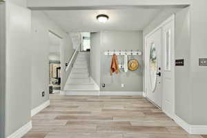 Entryway featuring a textured ceiling, wood finish floors, stairway, and a fireplace