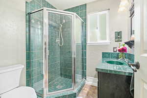 Full bathroom with a textured wall, vanity, a shower stall, and a textured ceiling
