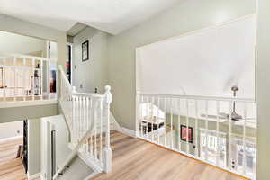 Staircase with wood finished floors and a textured ceiling