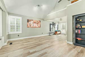 Unfurnished living room featuring light wood finished floors and high vaulted ceiling