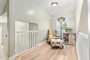 Living area with light wood finished floors, a textured ceiling, and an upstairs landing