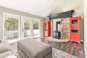 Living area with a wood stove, vaulted ceiling, and wood finished floors