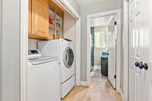 Washroom featuring a textured ceiling, light wood-type flooring, and washing machine and clothes dryer