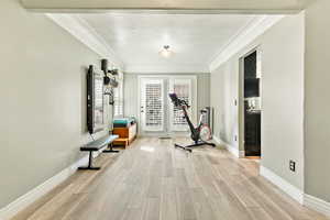 Hallway featuring crown molding, a textured ceiling, and light wood finished floors