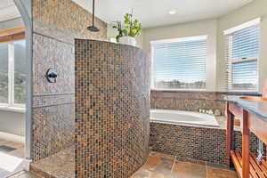 Bathroom featuring healthy amount of natural light, a tile shower, a bath, a textured ceiling, and tile walls