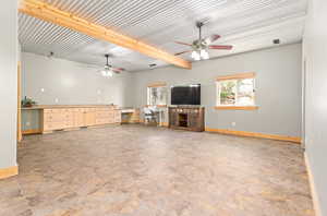 Unfurnished living room featuring baseboards and beamed ceiling