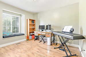 Office space featuring light wood finished floors and a textured ceiling