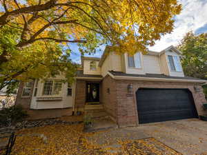 Traditional-style house featuring brick siding, a garage, driveway, and roof with shingles