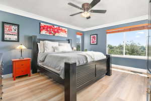 Bedroom with light wood-type flooring, a textured ceiling, and ceiling fan