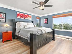 Bedroom with light wood-type flooring, a textured ceiling, and ceiling fan