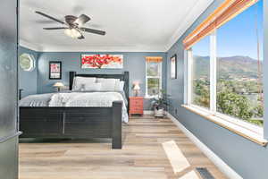 Bedroom with a mountain view, light wood-style floors, a textured ceiling, and a ceiling fan