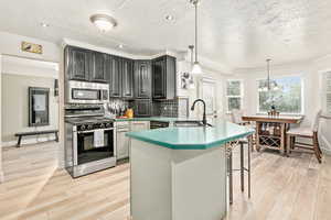 Kitchen with crown molding, a peninsula, appliances with stainless steel finishes, a textured ceiling, and decorative backsplash