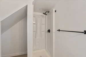 Bathroom featuring a textured ceiling and a stall shower