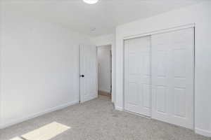 Unfurnished bedroom with light carpet and a closet