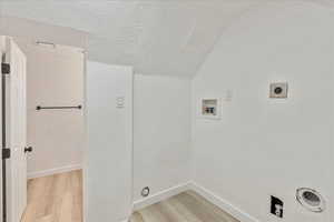 Washroom featuring light wood-style flooring, a textured ceiling, hookup for an electric dryer, and hookup for a washing machine