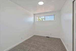 Carpeted spare room with baseboards and a textured ceiling