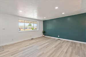 Spare room with light wood-style flooring, recessed lighting, and a textured ceiling