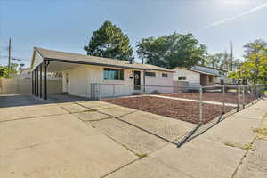 Ranch-style house featuring driveway, a gate, brick siding, and a carport