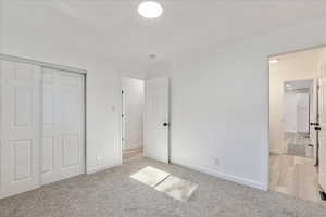 Unfurnished bedroom with a closet and light carpet
