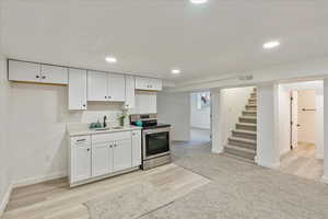 Kitchen featuring stainless steel range with electric cooktop, white cabinets, light countertops, recessed lighting, and light wood finished floors