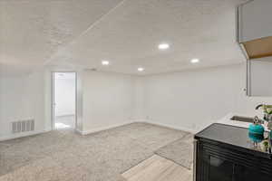 Bar area with a textured ceiling, black range with electric stovetop, recessed lighting, and light colored carpet