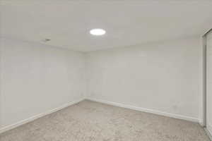 Unfurnished room with baseboards and light colored carpet