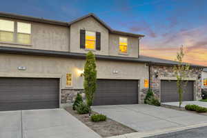 Traditional home with stone siding, stucco siding, and driveway