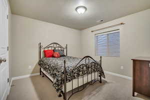 Bedroom featuring light colored carpet and a textured ceiling