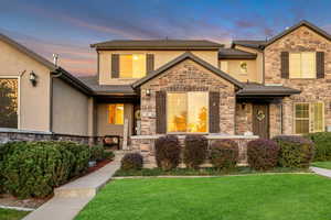 View of front facade featuring stone siding, a front lawn, and stucco siding