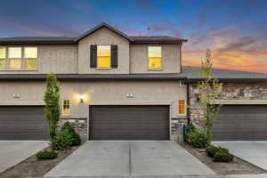 Traditional-style home with stone siding, stucco siding, and concrete driveway