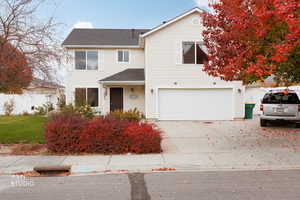Traditional home with a shingled roof, a garage, and driveway