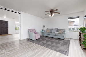 Living area with light wood-style floors and a ceiling fan