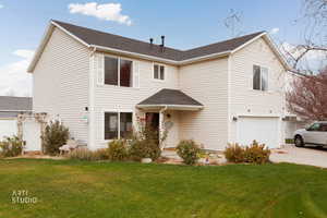 Traditional home featuring an attached garage, roof with shingles, and driveway