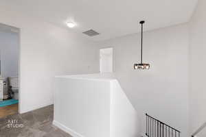 Hallway with carpet, a chandelier, and an upstairs landing