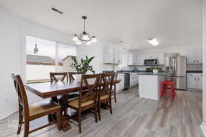 Dining area with light wood-style flooring and a chandelier