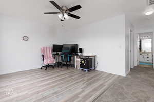 Office space with light wood-type flooring and a ceiling fan